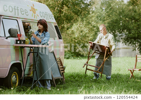 Biracial food truck colleagues preparing zone for orders under open sky 120554424
