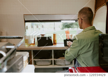 Back view of unrecognizable food truck worker preparing workspace for future orders Back view of unrecognizable food truck worker preparing workspace for future orders 120554429