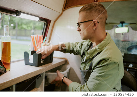 Side view of Caucasian young adult filling box with paper tissue while preparing for workday at food truck Side view of Caucasian young adult filling box with paper tissue while preparing for workday at food truck 120554430