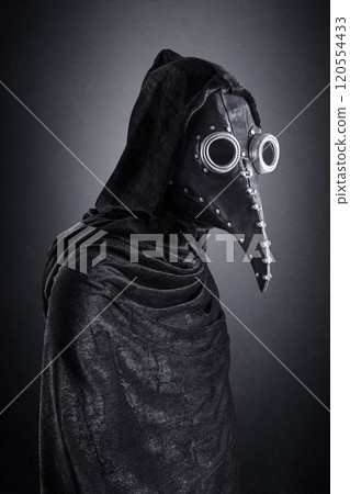 Plague doctor in hooded cloak at night over dark misty background Plague doctor in hooded cloak at night over dark misty background 120554433