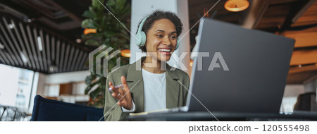 a woman wearing headphones is sitting in front of a laptop computer 120555498