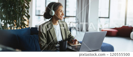 A woman in headphones sits in front of a laptop computer A woman in headphones sits in front of a laptop computer 120555500