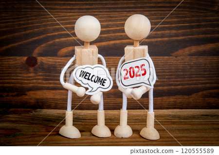 Welcome 2025 Concept. Two speech bubbles and miniature people on a wooden texture background 120555589