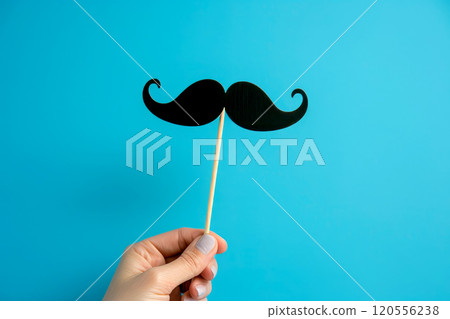 Happy fathers day, mustache on blue background. Woman hand holding festive party props, black little paper mustache on stick Happy fathers day, mustache on blue background. Woman hand holding festive party props, black little paper mustache on stick 120556238