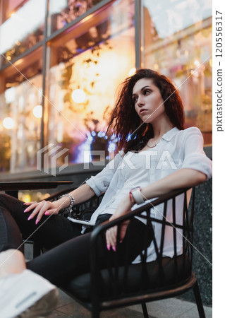 Woman relaxing at a stylish cafe in the evening glow of downtown 120556317