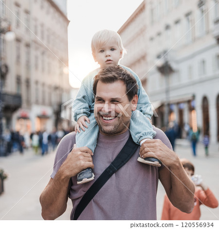 Portrait of smiling father carrying his toddler child piggyback around city on family vacations. Happy father's day Portrait of smiling father carrying his toddler child piggyback around city on family vacations. Happy father's day 120556934