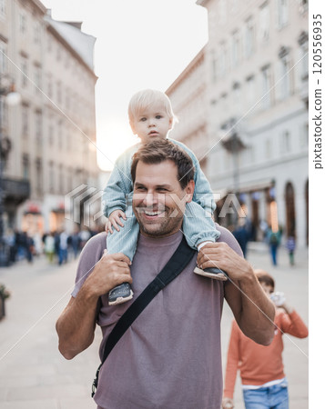 Portrait of smiling father carrying his toddler child piggyback around city on family vacations. Happy father's day 120556935