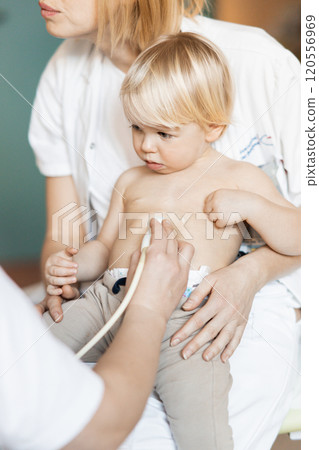 Small child being checked for heart murmur by heart ultrasound exam by cardiologist as part of regular medical checkout at pediatrician 120556969