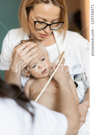 Small child being checked for heart murmur by heart ultrasound exam by cardiologist as part of regular medical checkout at pediatrician 120556971