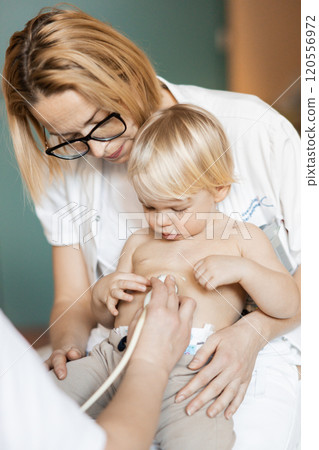 Small child being checked for heart murmur by heart ultrasound exam by cardiologist as part of regular medical checkout at pediatrician 120556972