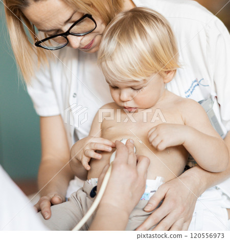Small child being checked for heart murmur by heart ultrasound exam by cardiologist as part of regular medical checkout at pediatrician 120556973