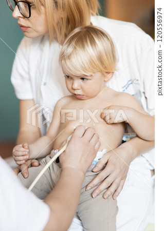 Small child being checked for heart murmur by heart ultrasound exam by cardiologist as part of regular medical checkout at pediatrician 120556974