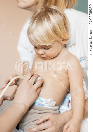 Small child being checked for heart murmur by heart ultrasound exam by cardiologist as part of regular medical checkout at pediatrician 120556989