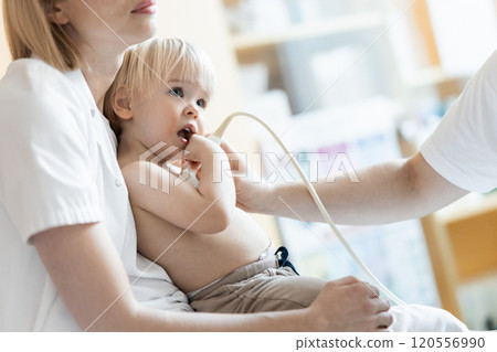 Small child being checked for heart murmur by heart ultrasound exam by cardiologist as part of regular medical checkout at pediatrician 120556990