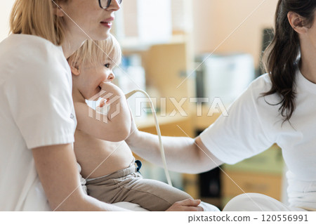 Small child being checked for heart murmur by heart ultrasound exam by cardiologist as part of regular medical checkout at pediatrician 120556991