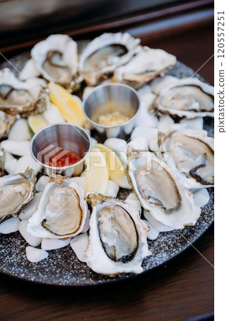 Fresh oysters on ice with lemon wedges and sauces, served elegantly for a seafood dining experience 120557251