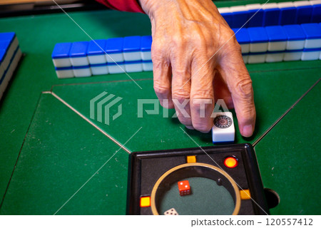 The hands of a senior playing mahjong on an electric mahjong table 120557412