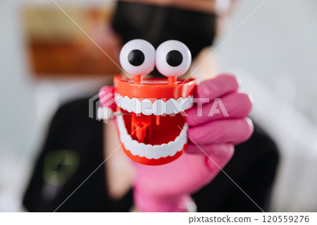 Fun dental education toy with animated teeth and googly eyes held by gloved hand in clinic setting Fun dental education toy with animated teeth and googly eyes held by gloved hand in clinic setting 120559276