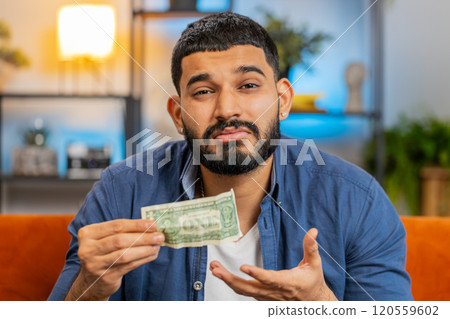 Hispanic man upset over insufficient amount of money showing one dollar banknote bankruptcy poverty 120559602