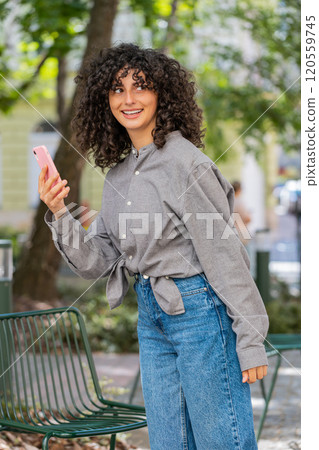 Tourist young curly hair woman using smartphone typing text messages looking for search a way on map Tourist young curly hair woman using smartphone typing text messages looking for search a way on map 120559745