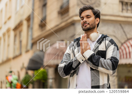 Religious Indian man praying with closed eyes to God asking for blessing while standing on street 120559864