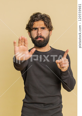 Hindu man says No hold palm in stop gesture, warning of finish prohibited access on beige background Hindu man says No hold palm in stop gesture, warning of finish prohibited access on beige background 120559981
