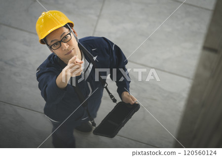 A middle-aged man in work clothes inspecting a building A middle-aged man in work clothes inspecting a building 120560124