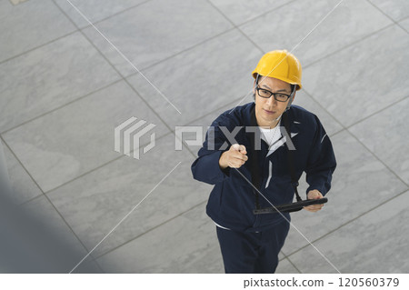 一名穿著工作服的中年男子正在檢查建築物 一名穿著工作服的中年男子正在檢查建築物 120560379
