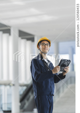 A middle-aged man in work clothes inspecting a building 120560433