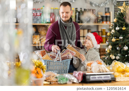 Dad and son are choosing sweets for New Year celebration in supermarket 120561614