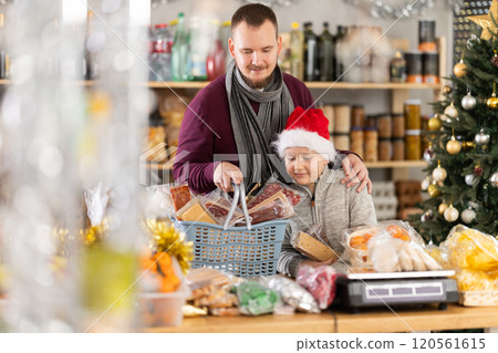 Dad and son are choosing sweets for New Year celebration in supermarket 120561615