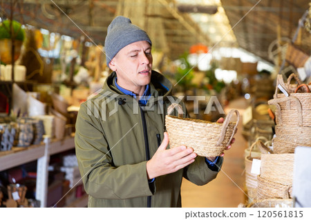 Man selecting wicker basket in salesroom of home goods store Man selecting wicker basket in salesroom of home goods store 120561815