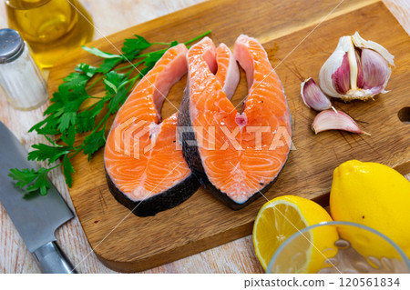 Salmon fillet on cutting board with lemon and parsley Salmon fillet on cutting board with lemon and parsley 120561834