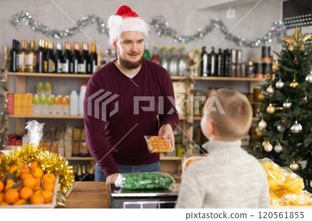 Salesman weighs candies in a supermarket 120561855