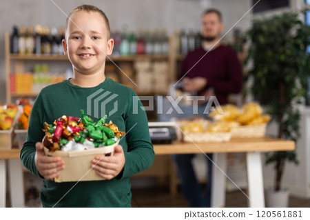 Little boy holding candies in grocery store 120561881