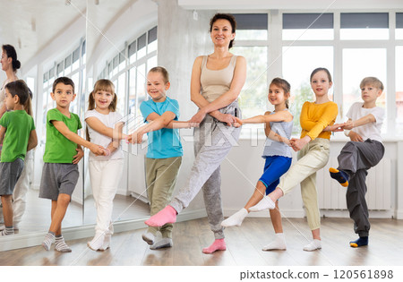 Group of children stand in row holding hands, performing Irish folk dance. 120561898