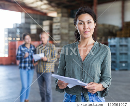 Woman and her colleagues standing in warehouse 120561927