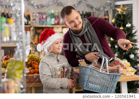 Dad and son are choosing products for New Year celebration in supermarket Dad and son are choosing products for New Year celebration in supermarket 120561941