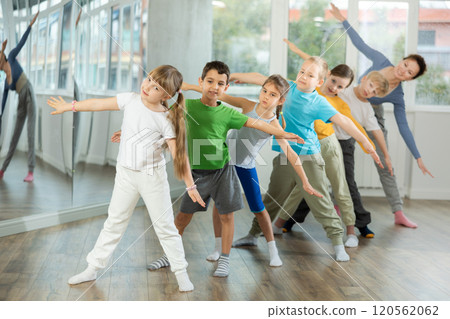 Children do warm-up exercises in studio, prepare for pair dance class Children do warm-up exercises in studio, prepare for pair dance class 120562062