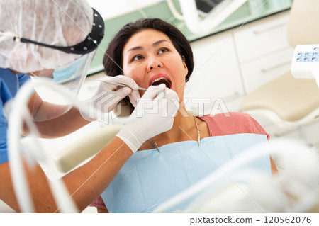 Dentist examines woman mouth at dental clinic 120562076
