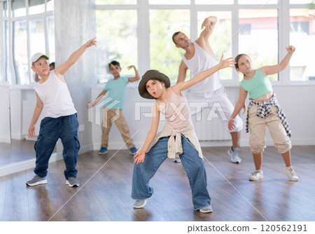 Young girl and group of positive children practicing energetic hip hop movements at dance school 120562191