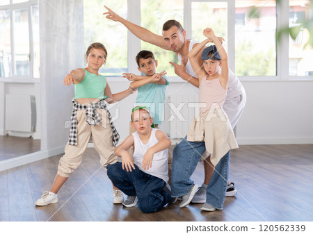 Happy group of young breakdancers artistically posing with male choreographer in bright hall 120562339