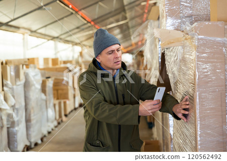 Warehouse worker photographing cardboard box with his phone Warehouse worker photographing cardboard box with his phone 120562492