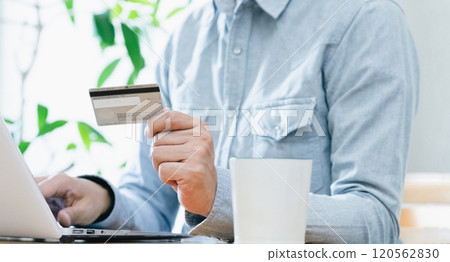 A man's hand looking at a credit card 120562830