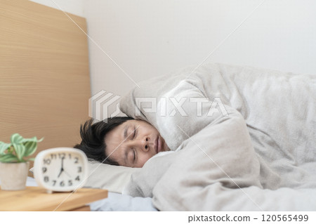 Man sleeping in bed; Man unable to get out of bed because it's too cold 120565499