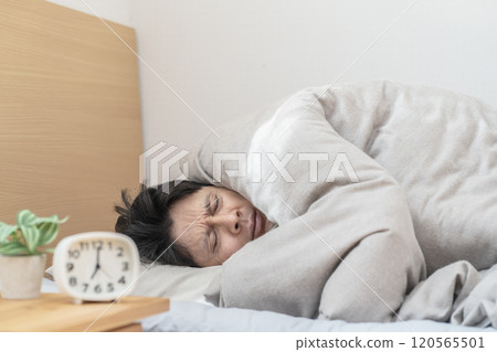Man sleeping in bed; Man unable to get out of bed because it's too cold 120565501