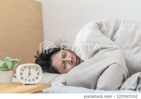 Man sleeping in bed; Man unable to get out of bed because it's too cold 120565502