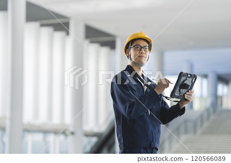一名穿著工作服的中年男子拿著平板電腦檢查建築物 120566089