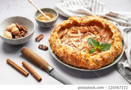 Delicious homemade apple galette decorated with almond flakes and fresh mint 120567372
