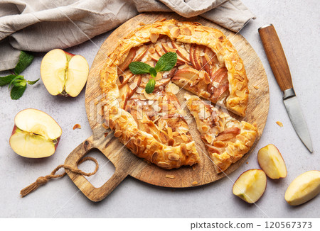 Delicious homemade apple galette with almond flakes and fresh mint on rustic wooden board 120567373